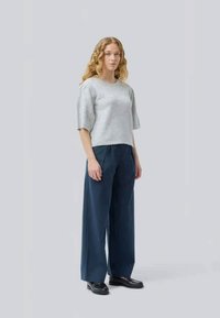 Haut gris à manches courtes et pantalon large marine avec une coupe décontractée, associés à des chaussures plates noires. Texture douce, lignes épurées, design minimaliste.