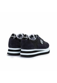 Donkerblauwe sneakers van een mix van suede en leer, met een wit en zwarte gestreepte zool, en een glanzende zwarte hak met logo.