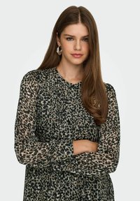Blouse imprimé léopard en tissu léger et transparent ; avec manches longues, détails plissés et encolure ronde. Souligné par des textures subtiles.