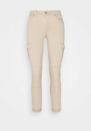 Beige slim-fit cargo pants with side flap pockets, front button, stitched knee detailing, and elastic cuffs at ankles.