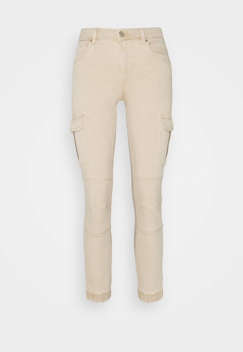Pantalon cargo beige coupe slim avec poches à rabat latérales, bouton sur le devant, détails cousus aux genoux et poignets élastiques aux chevilles.