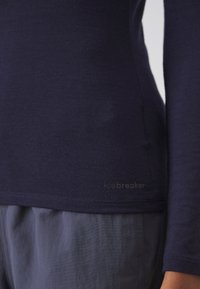 Marineblauwe longsleeve shirt gemaakt van zachte stof, met een aansluitend ontwerp, een gladde textuur en subtiele branding nabij de zoom.