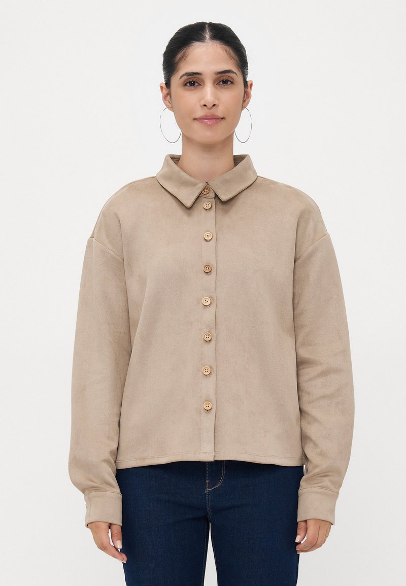 Beige button-up shirt with a collar, made of soft material, featuring wooden buttons and relaxed fit. Long sleeves with cuff detail.