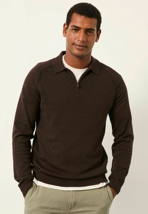 Brauner Pullover mit Reißverschluss und Kragen, gerippten Bündchen und Saum. Getragen über einem weißen Hemd, das eine glatte Textur und eine taillierte Passform aufweist.