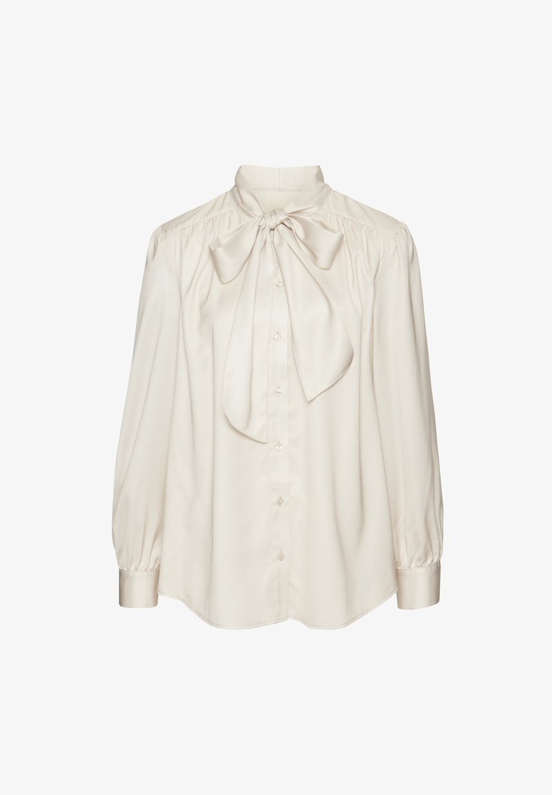 Blusa di seta color crema con un grande fiocco al colletto, chiusura con bottoni e maniche lunghe a sbuffo. Tessuto liscio con una vestibilità rilassata.