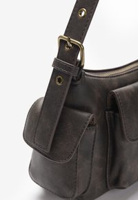 Ciemnobrązowa skórzana torba na ramię z regulowanym paskiem, mosiężną klamrą, zamknięciem na zamek błyskawiczny oraz dwoma przednimi kieszeniami z klapami.