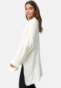 Kuscheliger, weißer Strickpullover mit langen Ärmeln, gerippten Bündchen und asymmetrischem Saum. Hat eine lockere, entspannte Passform und eine strukturierte Oberfläche.