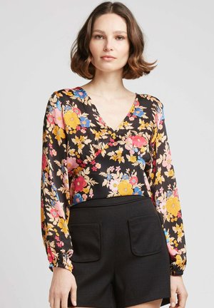 Blouse à manches longues en satin noir avec des fleurs vibrantes roses, jaunes et bleues ; design en V ; manches froncées ; texture lisse.