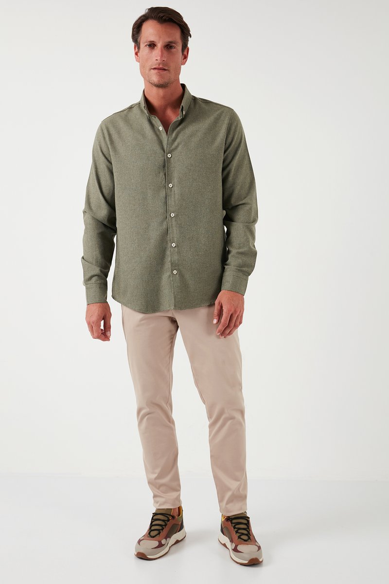 Camisa verde de botones, pantalones beig y zapatillas multicolores. La camisa cuenta con un collar y botones, con una textura suave.