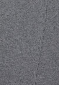 Grå stickad tyg med en slät textur, som har ett subtilt ribbat mönster och en vertikal sömdetalj. Mjukt, flexibelt material.