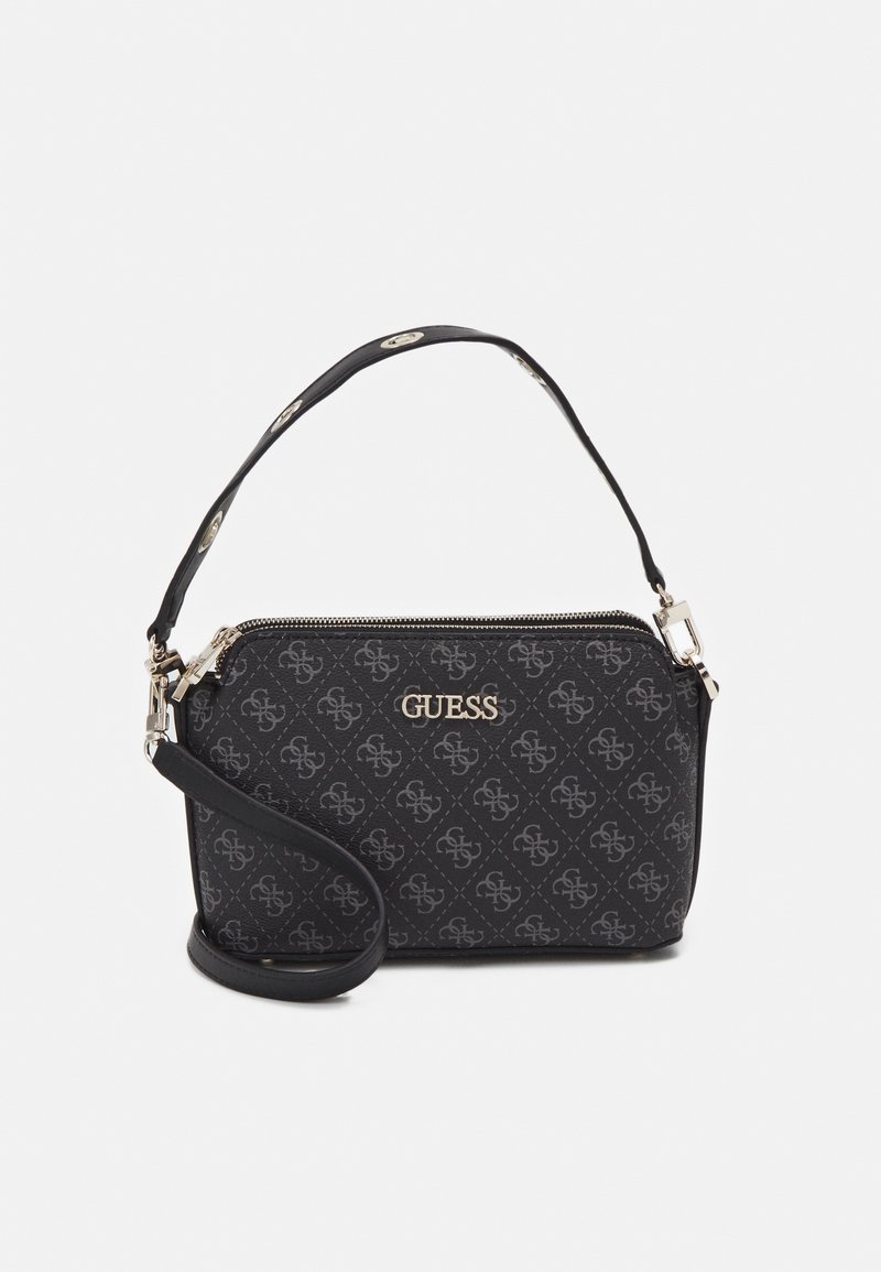 Pochette noire de la marque Guess avec motif logo intégral, garniture dorée, fermeture éclair et bracelet de poignet amovible sur fond blanc.