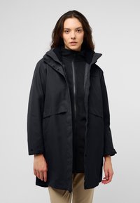 Giacca nera impermeabile con cappuccio, chiusura frontale a zip e due grandi tasche. Texture liscia, maniche lunghe fino a metà e polsini regolabili.