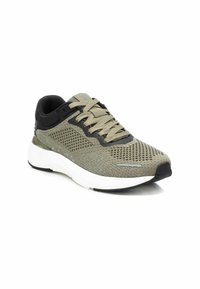 Zapatilla deportiva ligera con parte superior de malla verde, acentos negros, cuello acolchado y suela de goma blanca. Presenta una superficie texturizada y cordones.