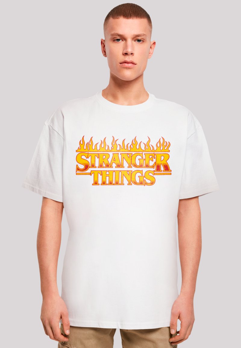 Weißes Baumwoll-T-Shirt mit auffälligem Design aus orangefarbenen und gelben Flammen um den Schriftzug "STRANGER THINGS", kurzen Ärmeln und einem lockeren Schnitt.