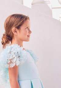 Hellblaues Kleid mit strukturierten Blumenakzenten an den Schultern, glattem Stoff, plissiertem Rock und dezenten, geprägten Details.