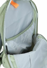 Intérieur d'un sac à dos vert avec une doublure grise claire, plusieurs compartiments et un tirette de fermeture éclair orange. Tissu texturé avec coutures renforcées.