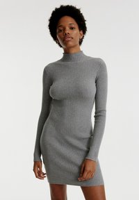 Graues, geripptes Kleid mit hohem Kragen und langen Ärmeln, taillierte Form und strukturierten Stoff. Entworfen für ein elegantes, schlankes Erscheinungsbild.