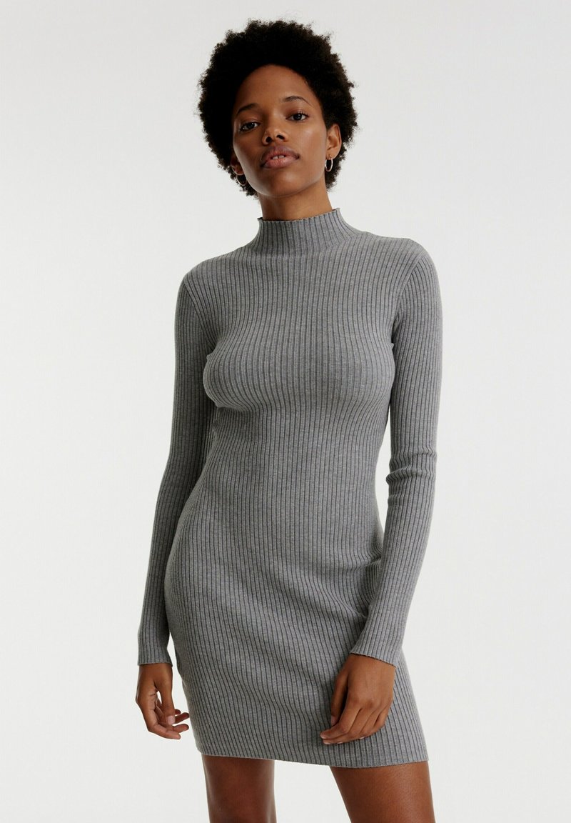 Graues, geripptes Kleid mit hohem Kragen und langen Ärmeln, taillierte Form und strukturierten Stoff. Entworfen für ein elegantes, schlankes Erscheinungsbild.