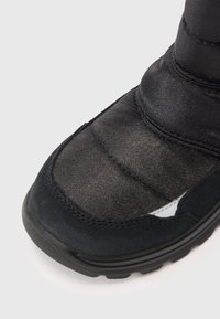 Sort vandtæt støvle med en polstret nylonoverdel, tekstureret ruskinds tå og gummisål. Har stikninger og en buet silhuet.