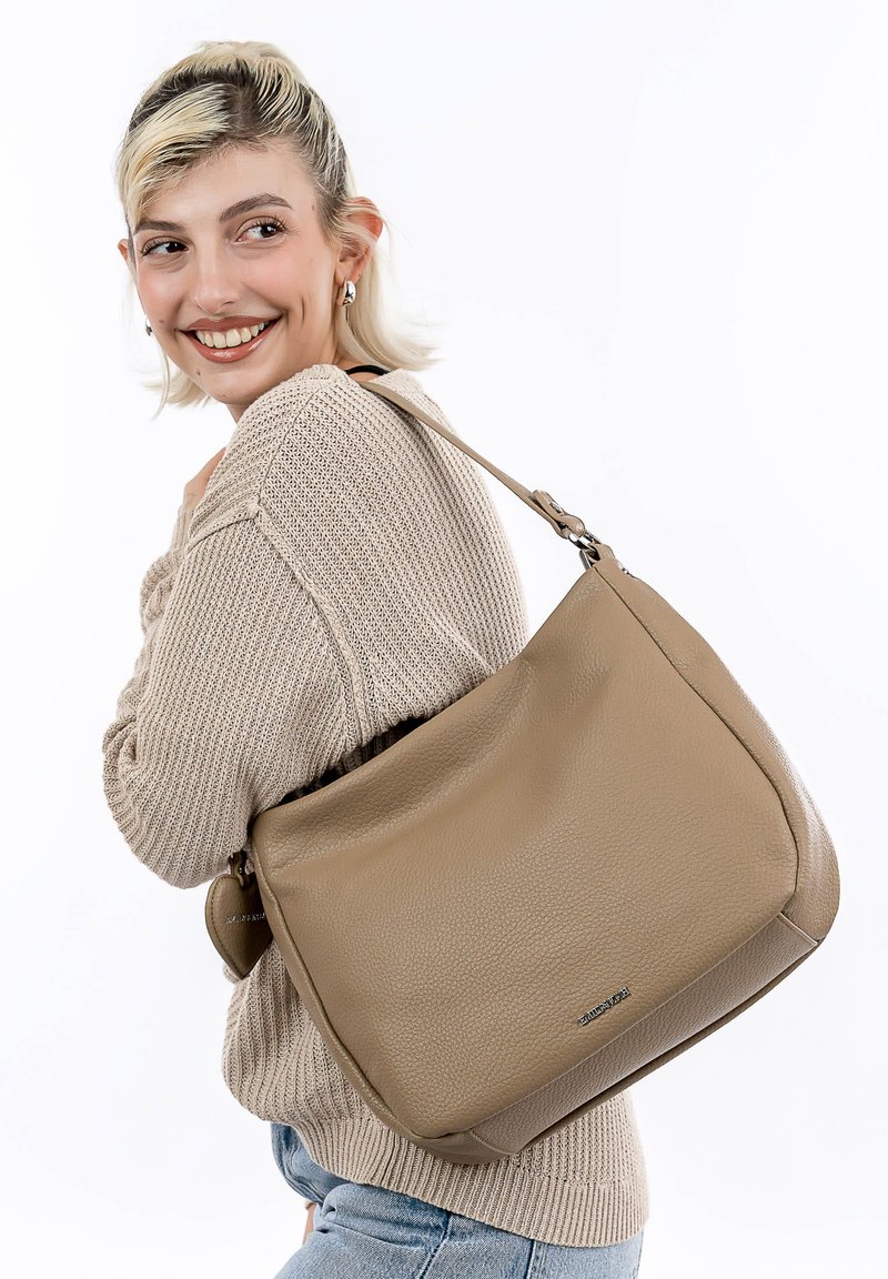 Sac à bandoulière en cuir beige avec une surface texturée, doté d'une seule bandoulière et d'un logo discret. Forme arrondie et accents lisses.