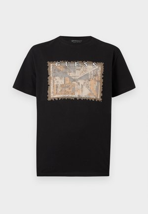 Crna pamučna majica s teksturiranim, pravokutnim grafičkim printom u bež i plavoj boji, s natpisima "GUESS" i "LOS ANGELES" u podebljanoj bijeloj boji.