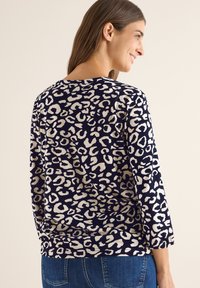 Maglietta a maniche lunghe blu marina con stampa leopardata beige, caratterizzata da un collo a giro e una vestibilità rilassata. Tessuto misto cotone con texture morbida.