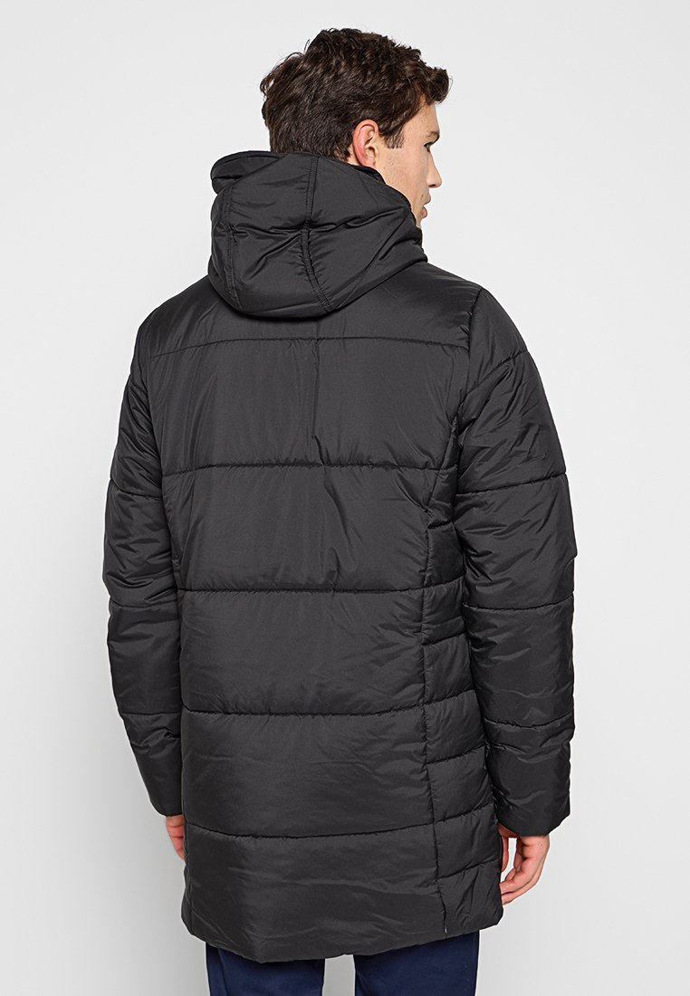 Abrigo acolchado negro con capucha ajustable, diseño acolchado y textura suave. Presenta costuras horizontales y un dorso ligeramente alargado.