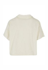Gekürztes Kurzarmhemd aus weichem, cremefarbenem Stoff mit einem umschlagbaren Kragen. Glatte Textur mit klarer Silhouette und minimalistischem Design.