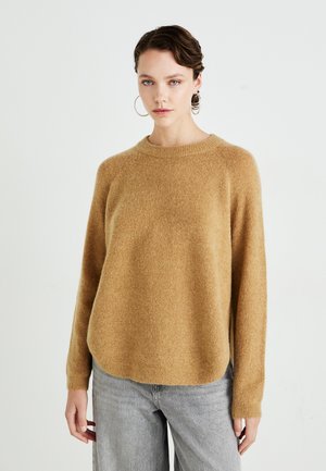 Langermet genser med rund hals i mykt, lysebrunt materiale med en avslappet passform. Teksturert overflate. Kombinert med lysegrå, vide jeans.