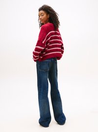Pull en tricot rayé rouge et rose, avec une coupe décontractée et un col rond, associé à un jean en denim à large jambe.