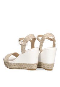 Sandalias de cuña blancas con acentos de yute trenzado, una correa texturizada y una superficie superior lisa. El tacón mide aproximadamente 7 cm de altura.