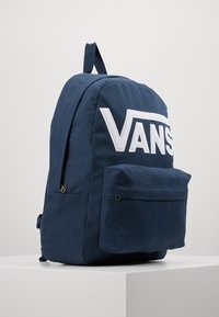 Zaino blu navy realizzato in tessuto resistente, con un grande logo bianco, tasca anteriore e spallacci regolabili per il trasporto.