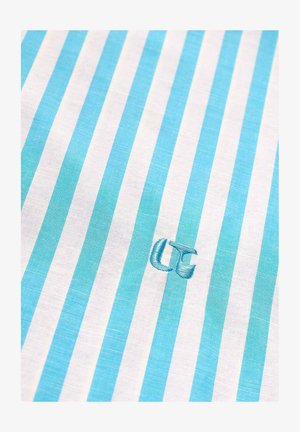 Tissu à rayures verticales bleues et blanches avec les initiales "UC" brodées en bleu près du centre.