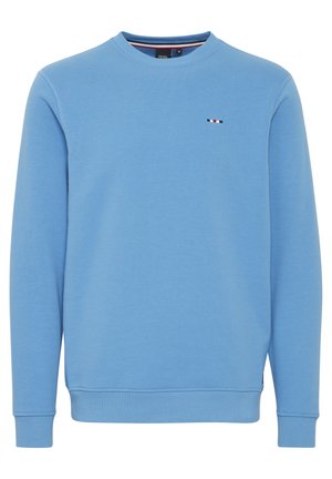 Gaiši zils džemperis ar apaļu kakla izgriezumu, garām piedurknēm un mazu daudzkrāsainu logotipu uz krūšu daļas. Gluda auduma tekstūra.