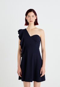 Vestido azul-marinho de um ombro, com detalhe de folhos à esquerda. Corpete justo, saia larga, feito de um tecido suave com um brilho subtil.