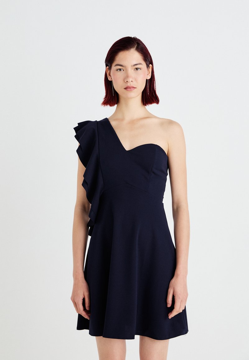 Vestido azul-marinho de um ombro, com detalhe de folhos à esquerda. Corpete justo, saia larga, feito de um tecido suave com um brilho subtil.