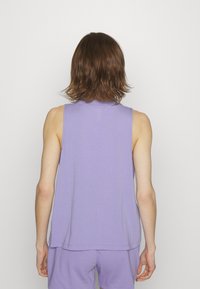 Top viola senza maniche realizzato in un tessuto morbido con una vestibilità rilassata, caratterizzato da un colletto alto e orli cuciti, abbinato a pantaloni corti coordinati.