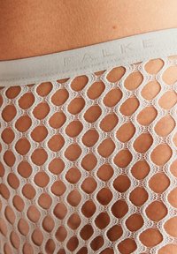 Spitzen-Fischernetzstrümpfe mit hexagonalem Muster in off-white, mit einem weichen, elastischen Taillenbund, der mit dem Markennamen versehen ist.