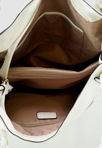 Witte faux leren tasinterieur met een lichtbruin stoffen voering, voorzien van een ritszak en één open zak voor organisatie.