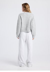 Light gray knitted sweater with loose fit and dropped shoulders, paired with soft, wide-leg, light gray sweatpants.