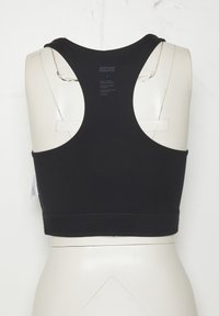 Fekete racerback sportmelltartó fehér manöken torsón, a hátulja látható, alul márkázott rugalmas szalaggal.