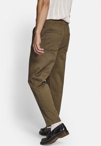 Olijfgroene, comfortabel zittende broek met een trekkoord in de taille. Beschikt over twee achterzakken en een gladde, stevige stoftextuur.