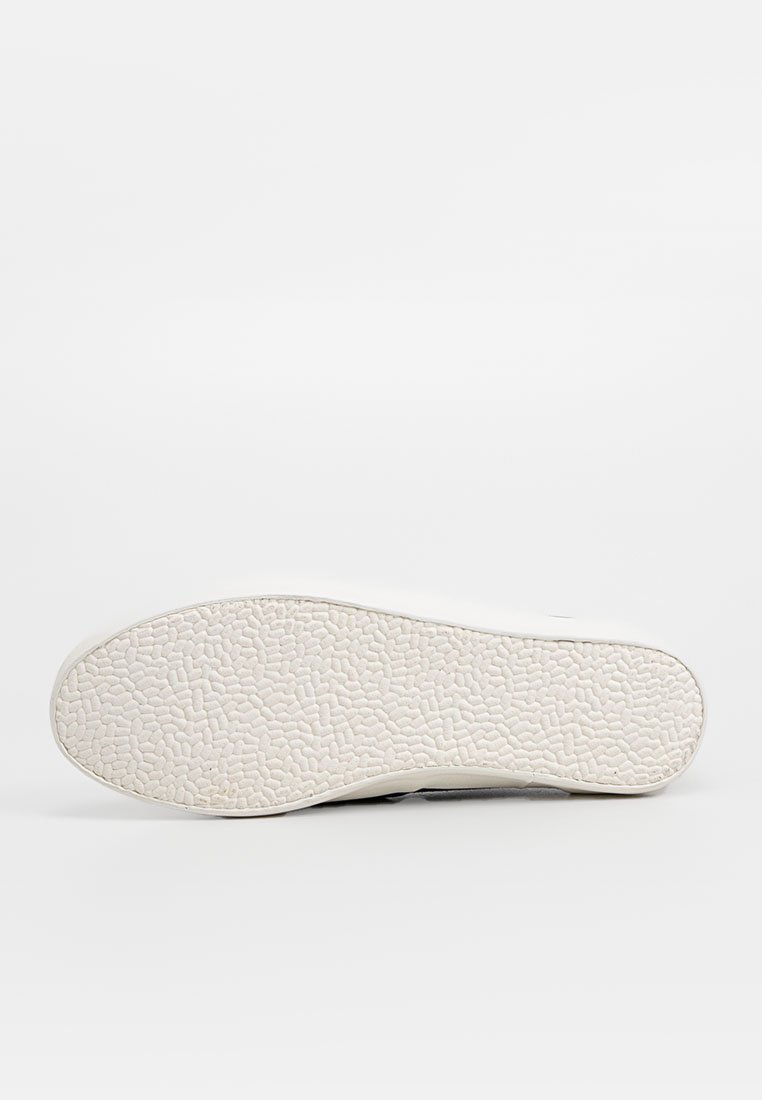 Suela de una zapatilla blanca con un patrón texturizado similar a guijarros, presentada sobre un fondo blanco liso.