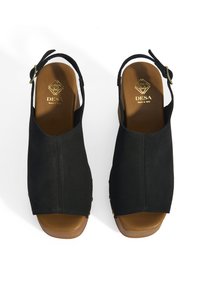 Schwarze Wildleder Sandalen mit offenen Zehen und Slingback-Design, ausgestattet mit einer goldfarbenen Metallschnalle und braunen Innensohlen, die eine glatte Textur aufweisen.