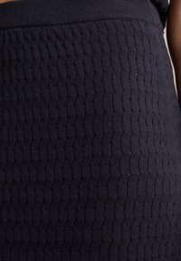 Marineblaue Texturrock mit einem Wabenmuster und einem glatten, elastischen Bund, hergestellt aus einem dehnbaren Stoff.