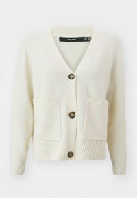 Överdimensionerad, krämfärgad cardigan i mjukt stickat tyg. Har en V-ringning, tre knappar, ribbade ärmslut och två framfickor.