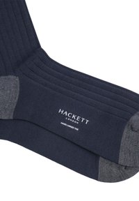 Calcetines de canalé color marino con un talón y puntera grises. Incluyen el logo "Hackett" y un detalle de "puntera cosida a mano" cerca del tobillo.