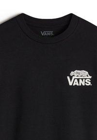 Camiseta de algodón negra con cuello redondo, con un gráfico de un tigre blanco y el logotipo "VANS" impreso en el lado izquierdo del pecho. Textura suave.