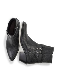 Botines negros de cuero texturizado con puntera afilada, tacón bajo y bloque, y detalle de hebilla metálica en el lateral.