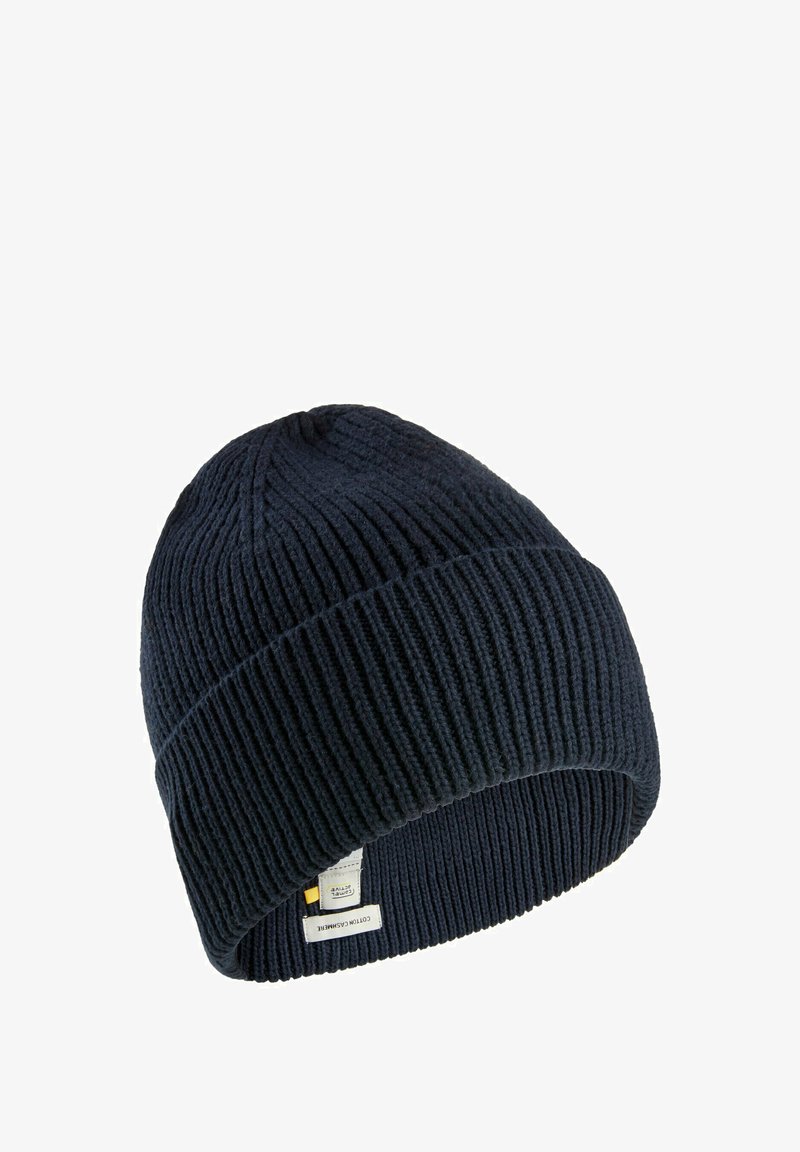 Navy knitted beanie hat with ribbed texture and a fold-over cuff. Features a label on the side with text and logo details.